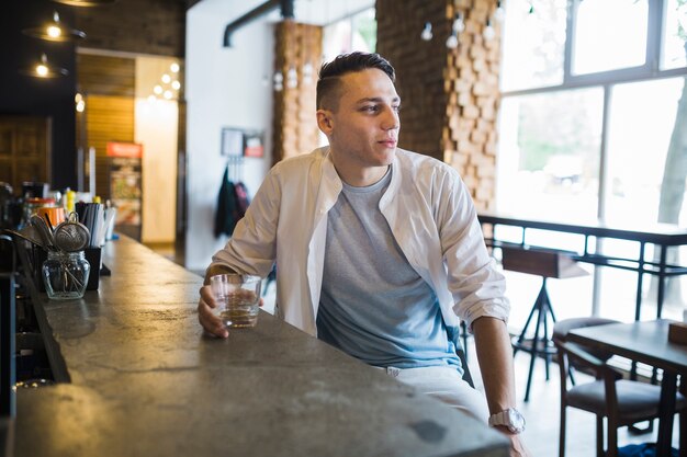 Joven sentado en la barra de bar en el restaurante