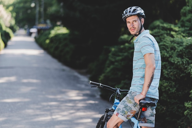 Foto gratuita joven sentado en bicicleta con casco protector