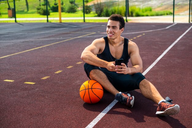 Joven sentado en la cancha de baloncesto