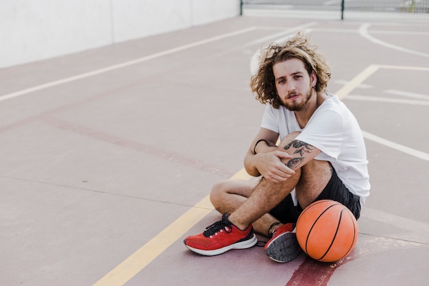 Joven, sentado, en, corte, con, baloncesto