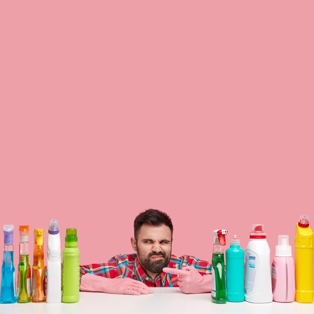 Joven sentado junto a productos de limpieza