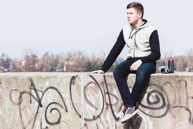 Joven sentado en la pared de graffiti