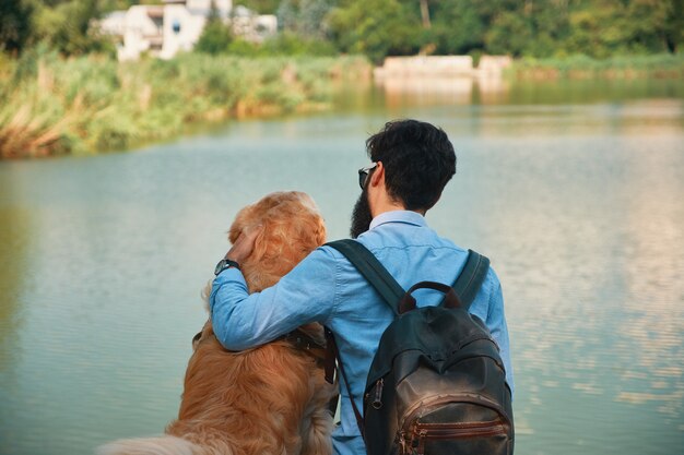 Joven sentado con su perro en la silla en el parque