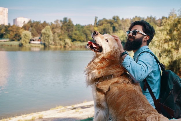 Foto gratuita joven sentado con su perro en la silla en el parque