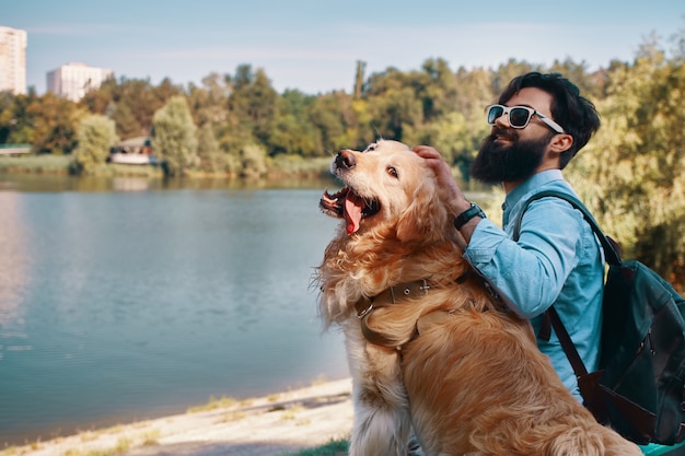 Joven sentado con su perro en la silla en el parque