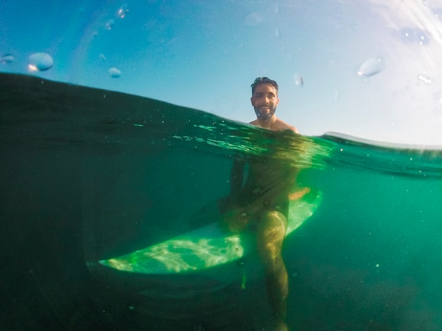 Joven, sentado, en, tabla de surf, en, agua