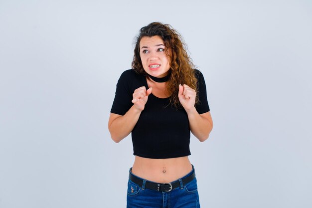 La joven se siente feliz levantando los puños sobre fondo blanco.