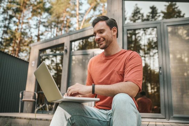 Joven sintiéndose positivo y trabajando en una computadora portátil