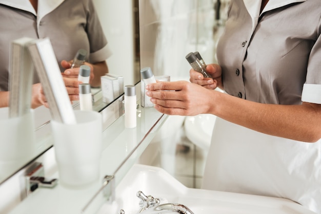 Joven sirvienta del hotel poniendo accesorios de baño en un baño