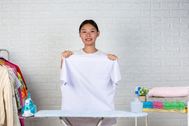 Una joven sirvienta que está preparando una camisa en su tabla de planchar con un ladrillo blanco.