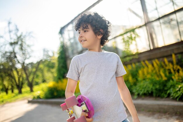 Joven skater con la tabla en la mano mirando hacia otro lado