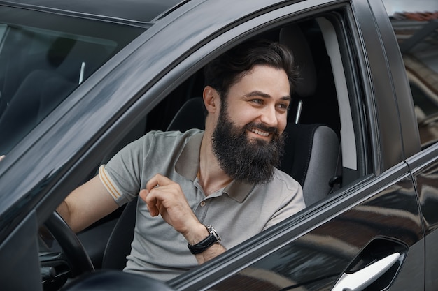 Joven sonriendo mientras conduce un auto