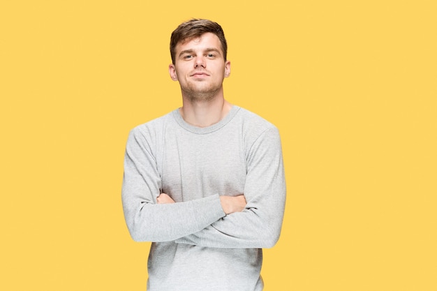 El joven sonriendo y mirando a cámara sobre fondo amarillo de estudio