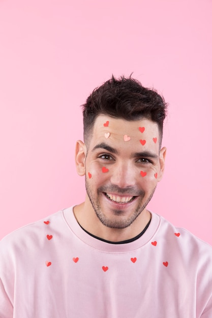 Joven sonriente con corazones de papel en la cara