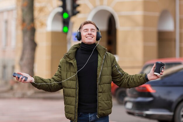 Joven sonriente escuchando música con auriculares en las calles