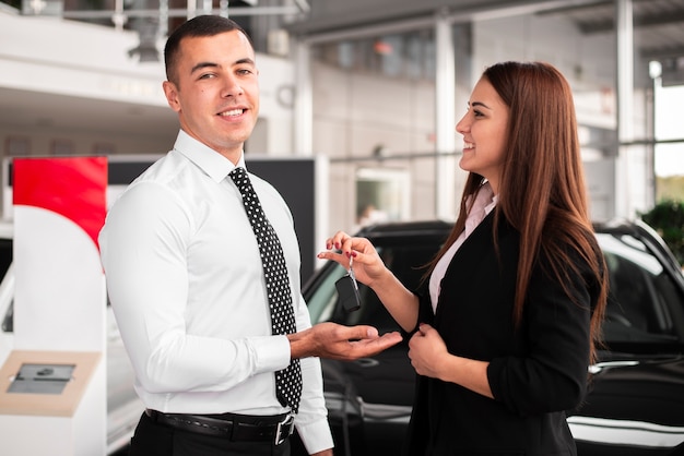 Foto gratuita joven sonriente feliz por su auto nuevo