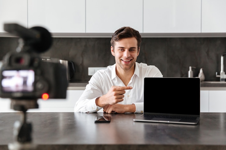 Foto gratuito un joven sonriente filmando su episodio de video blog