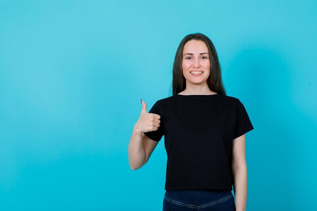 Una joven sonriente muestra un gesto perfecto en el fondo azul