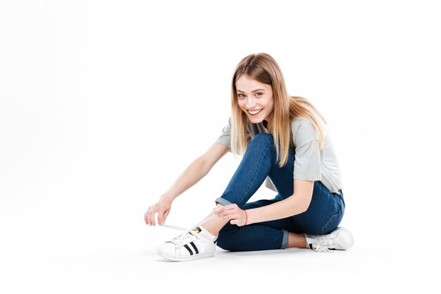 Joven sonriente mujer atar cordones de los zapatos