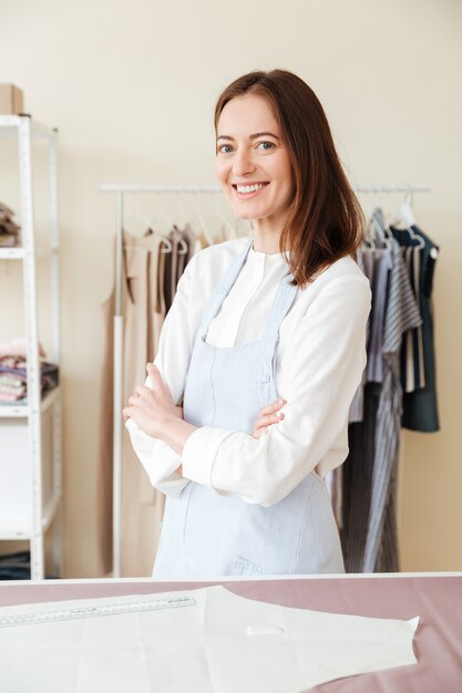 Joven sonriente mujer costurera mirando