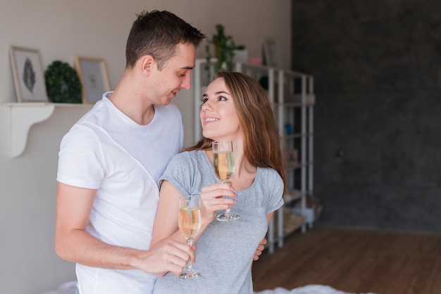 Foto gratuita joven sonriente pareja abrazándose con gafas en casa