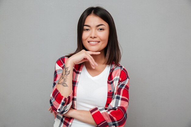 Joven sonriente de pie sobre la pared gris