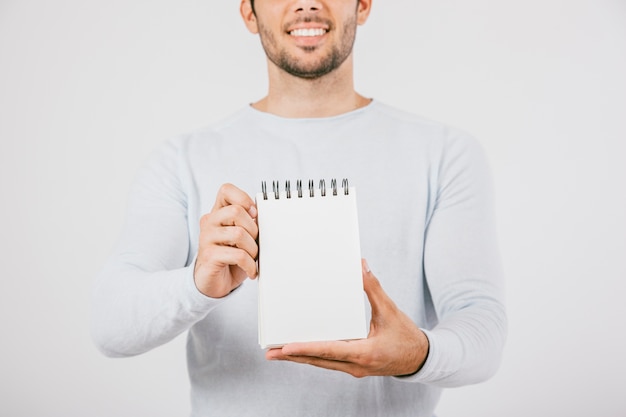 Foto gratuita joven sonriente sosteniendo una libreta