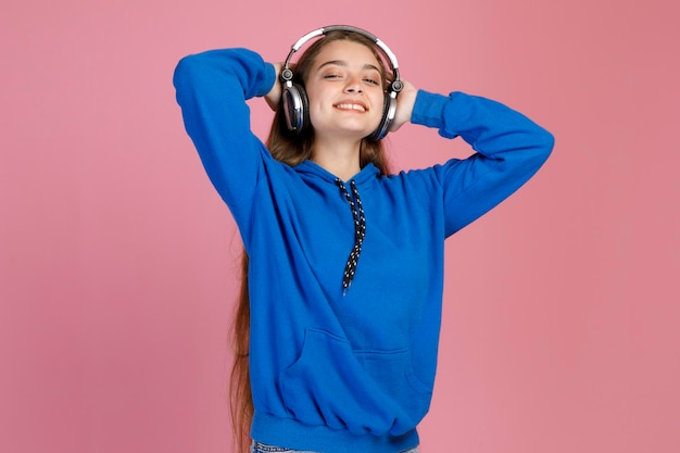 Foto gratuita joven sonriente tirando las manos detrás de la cabeza mientras disfruta de su canción favorita con auriculares en el interior