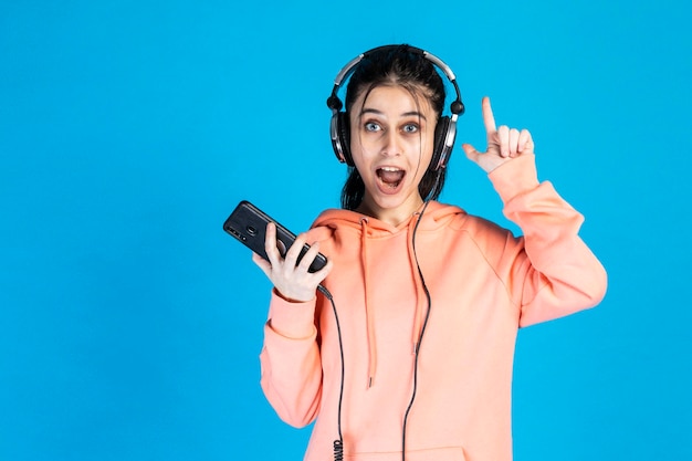 Una joven sorprendida con auriculares y levantó el dedo