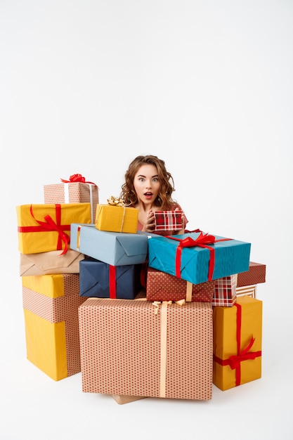 Foto gratuita joven sorprendida mujer rizada entre cajas de regalo