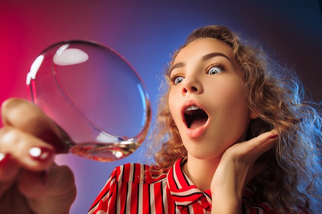 La joven sorprendida en ropa de fiesta posando con copa de vino.