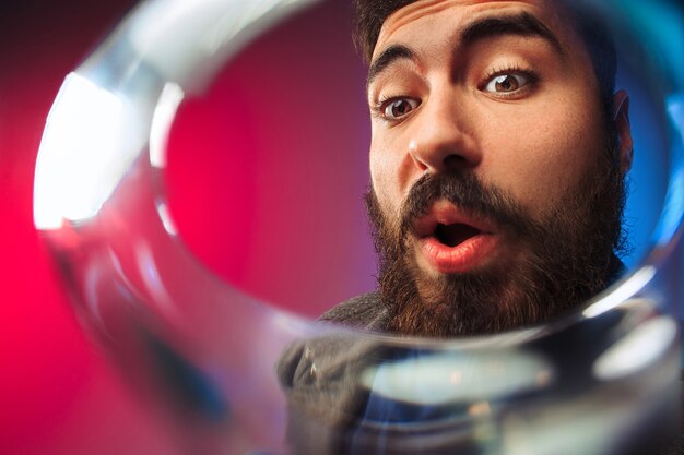 El joven sorprendido en ropa de fiesta posando con copa de vino.