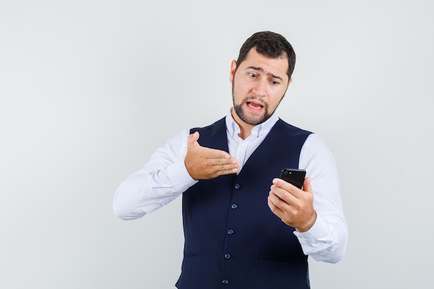 Joven sosteniendo a alguien responsable en el chat de video en camisa, chaleco