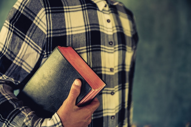 Foto gratuita un joven sosteniendo una biblia en sus manos.