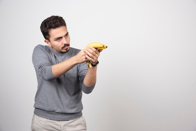 Un joven sosteniendo dos plátanos frescos.