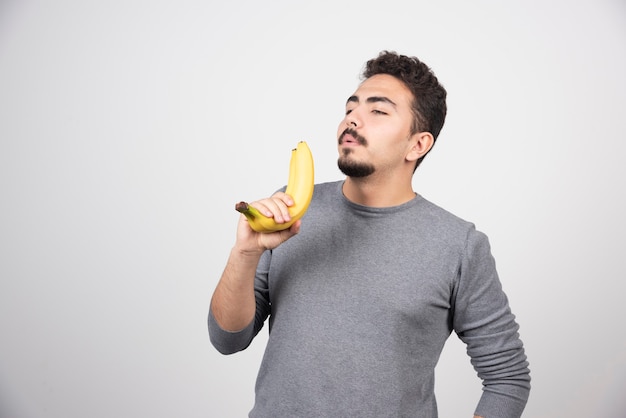 Un joven sosteniendo dos plátanos frescos.