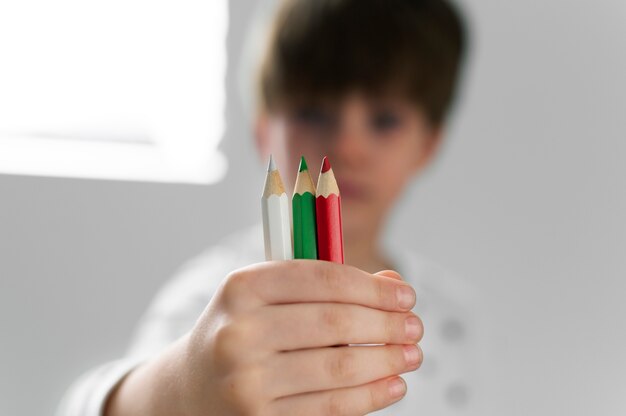 Joven sosteniendo lápices con los colores de la bandera búlgara