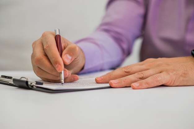 Joven sosteniendo un lápiz, escribiendo en un papel en el diario