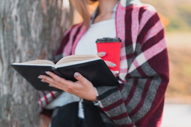 Joven sosteniendo un libro en el bosque