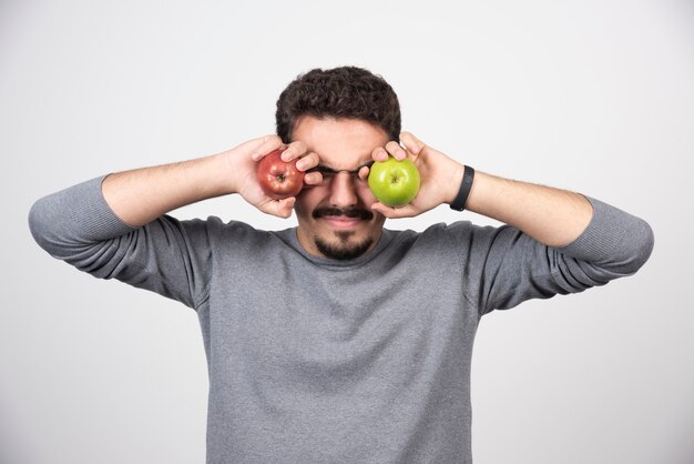 Joven sosteniendo manzanas verdes y rojas.