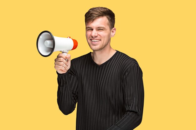 El joven sosteniendo un megáfono sobre fondo amarillo