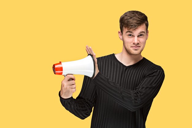 El joven sosteniendo un megáfono sobre fondo amarillo