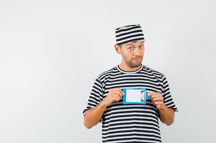 Foto gratuito joven sosteniendo mini portapapeles con sombrero de camiseta a rayas