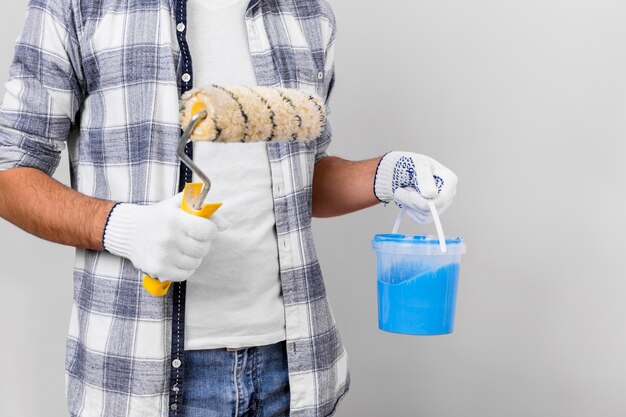 Joven sosteniendo pintura y rodillo de pintura