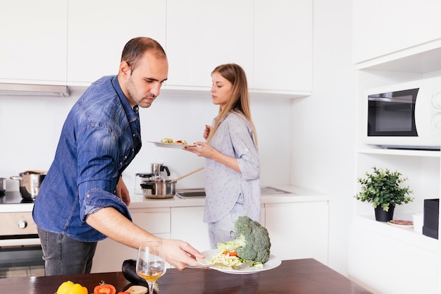 Joven sosteniendo un plato de ensalada en la cocina