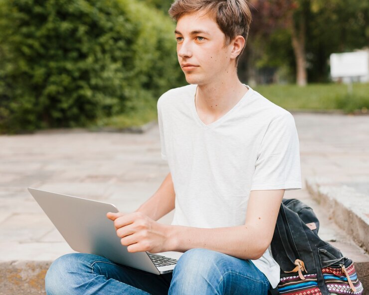 Foto gratuito joven sosteniendo portátil en el parque