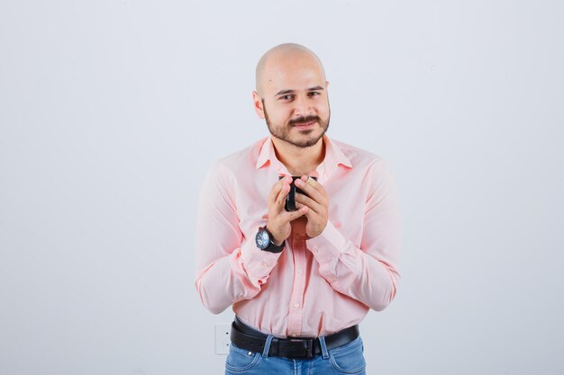 Joven sosteniendo la taza en camisa rosa, jeans, vista frontal.