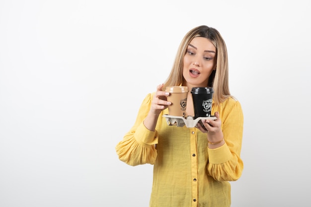 joven sosteniendo tazas de café y mirando la tapa.