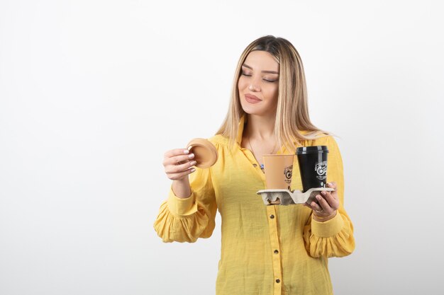 joven sosteniendo tazas de café y mirando la tapa.