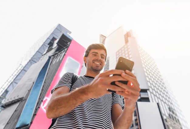 Joven sosteniendo un teléfono inteligente con ambas manos